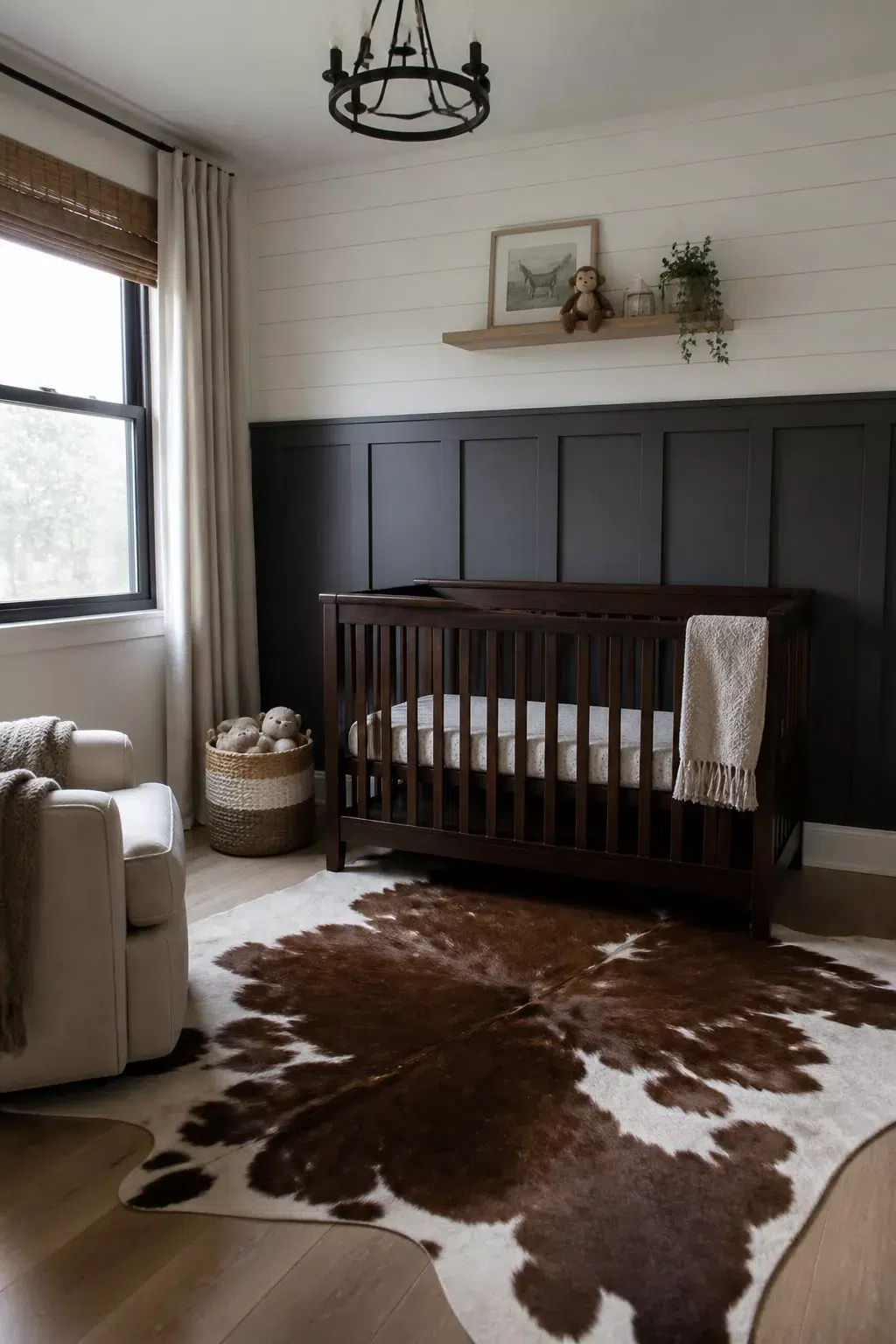 Charcoal board and batten nursery walls with white shiplap above, dark wood crib, and cowhide rug.