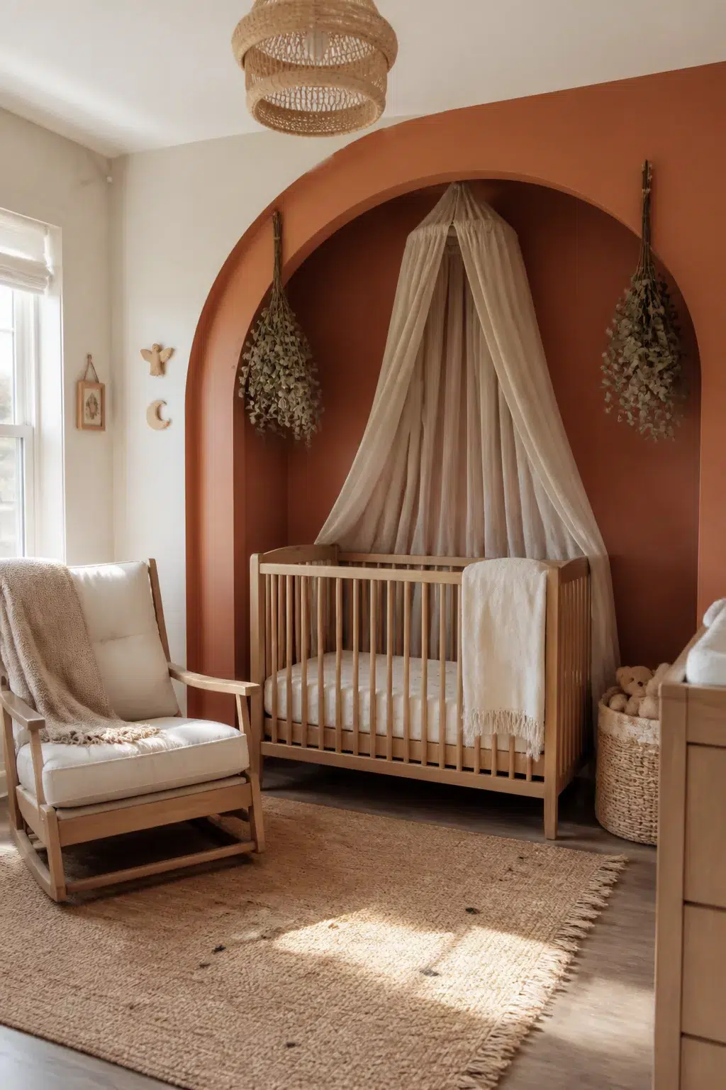 Boho accent wall nursery with painted terracotta arch nook, draped canopy crib, and dried eucalyptus bundles.