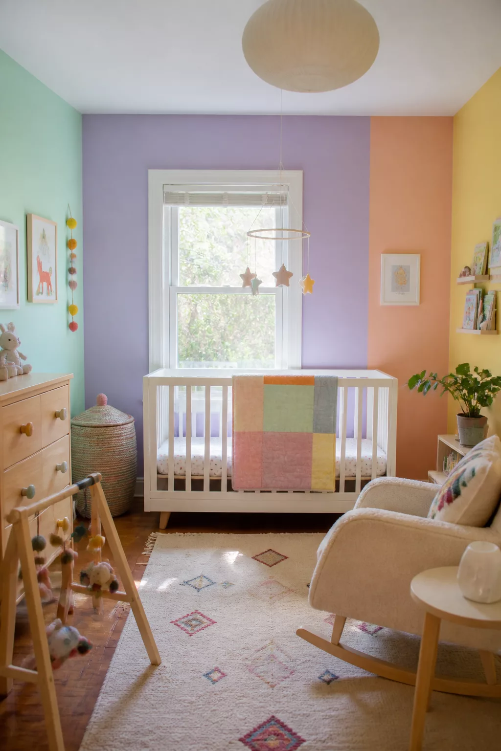 Colorful nursery ideas featuring pastel color block walls in mint, lavender, peach, and yellow with white crib.