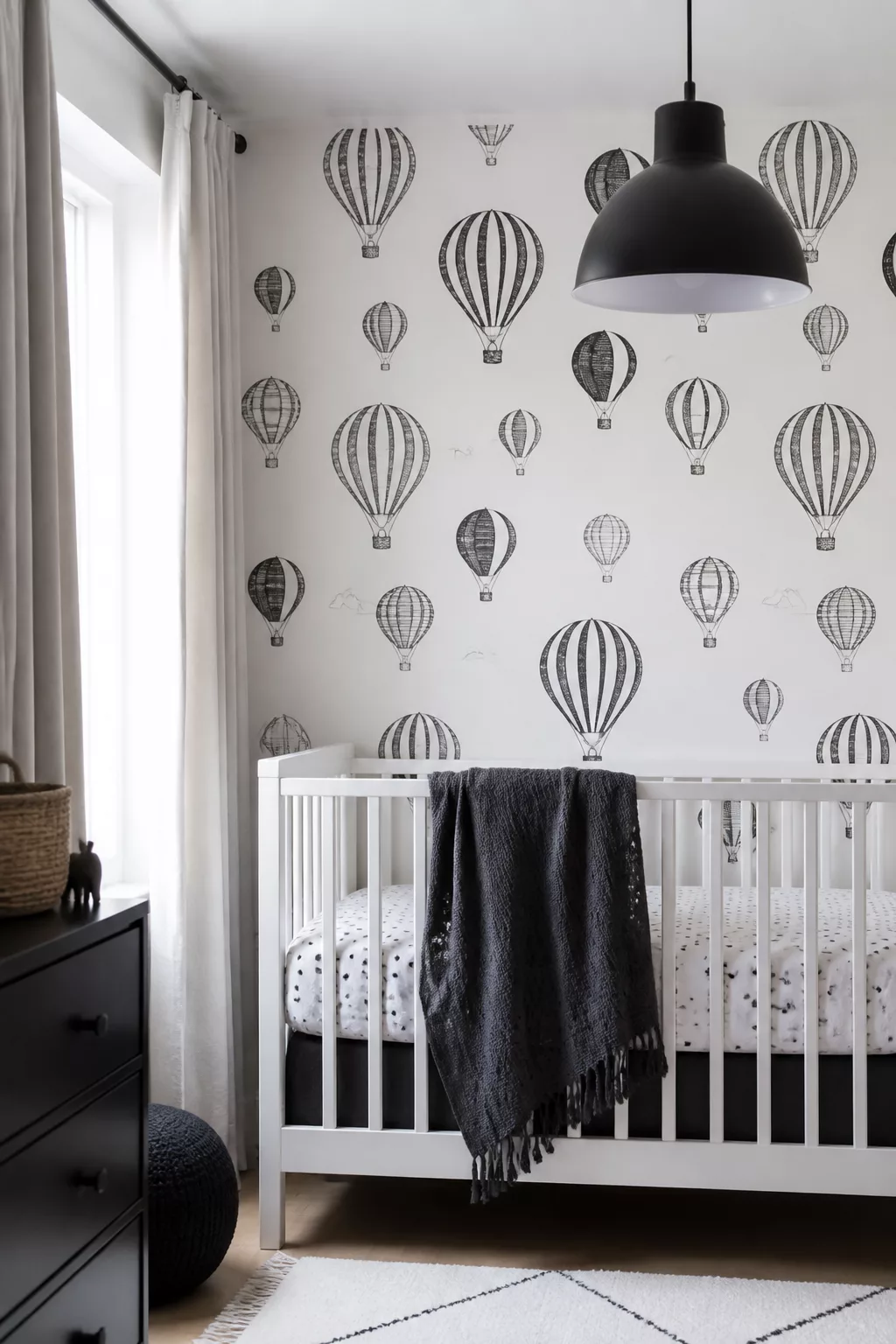 Black and white hot air balloon nursery ideas with graphic wallpaper, white crib, and black pendant light