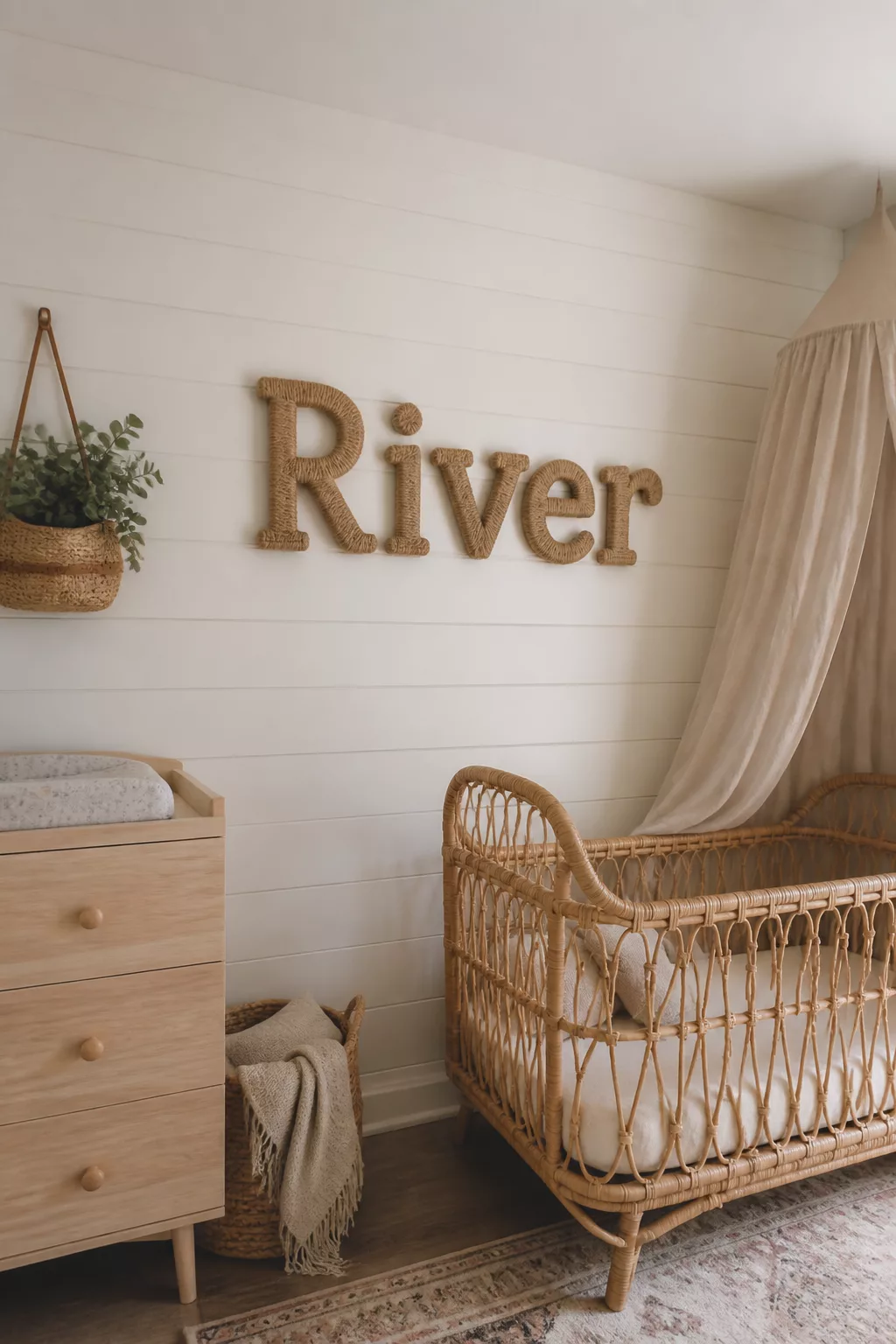Woven rope block letter nursery name sign on shiplap wall above rattan crib — nursery name signs idea.