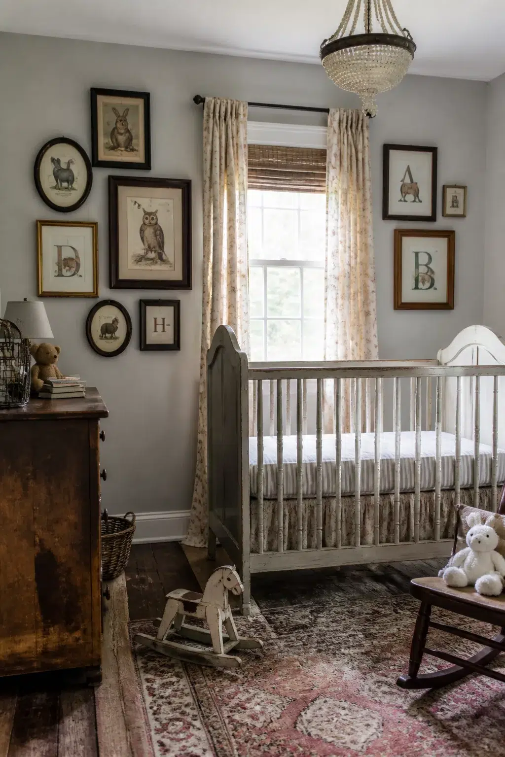 Vintage nursery ideas with framed animal prints gallery wall, crystal chandelier, gray crib, and Persian rug.