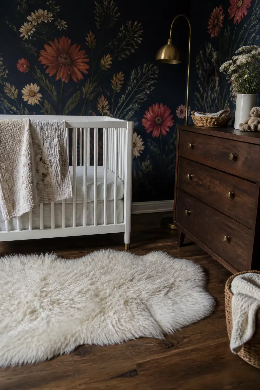 Dark navy floral wallpaper wildflower nursery design with white crib, walnut dresser, and shearling rug