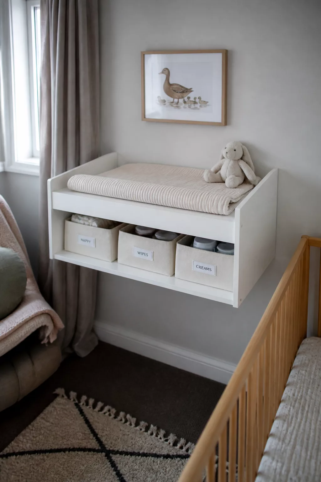 Wall-mounted floating changing table nursery ideas with labeled storage bins, gray walls, and a wood crib