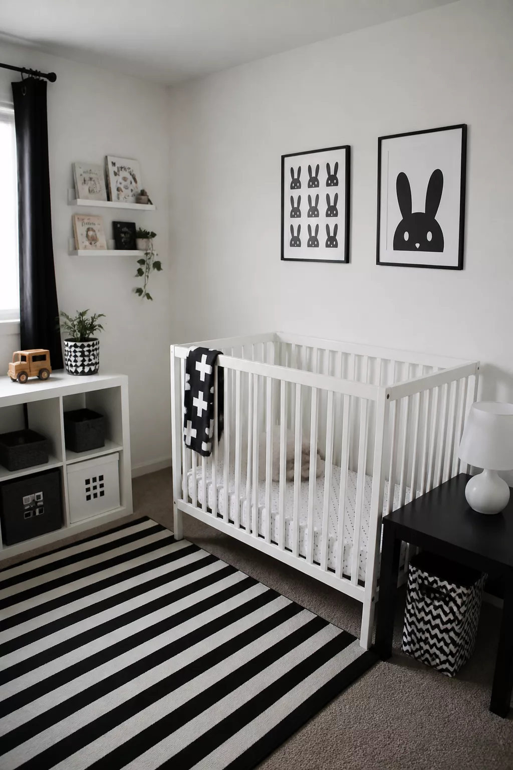 Monochrome IKEA nursery with white crib, black stripe rug, and black-framed bunny wall art
