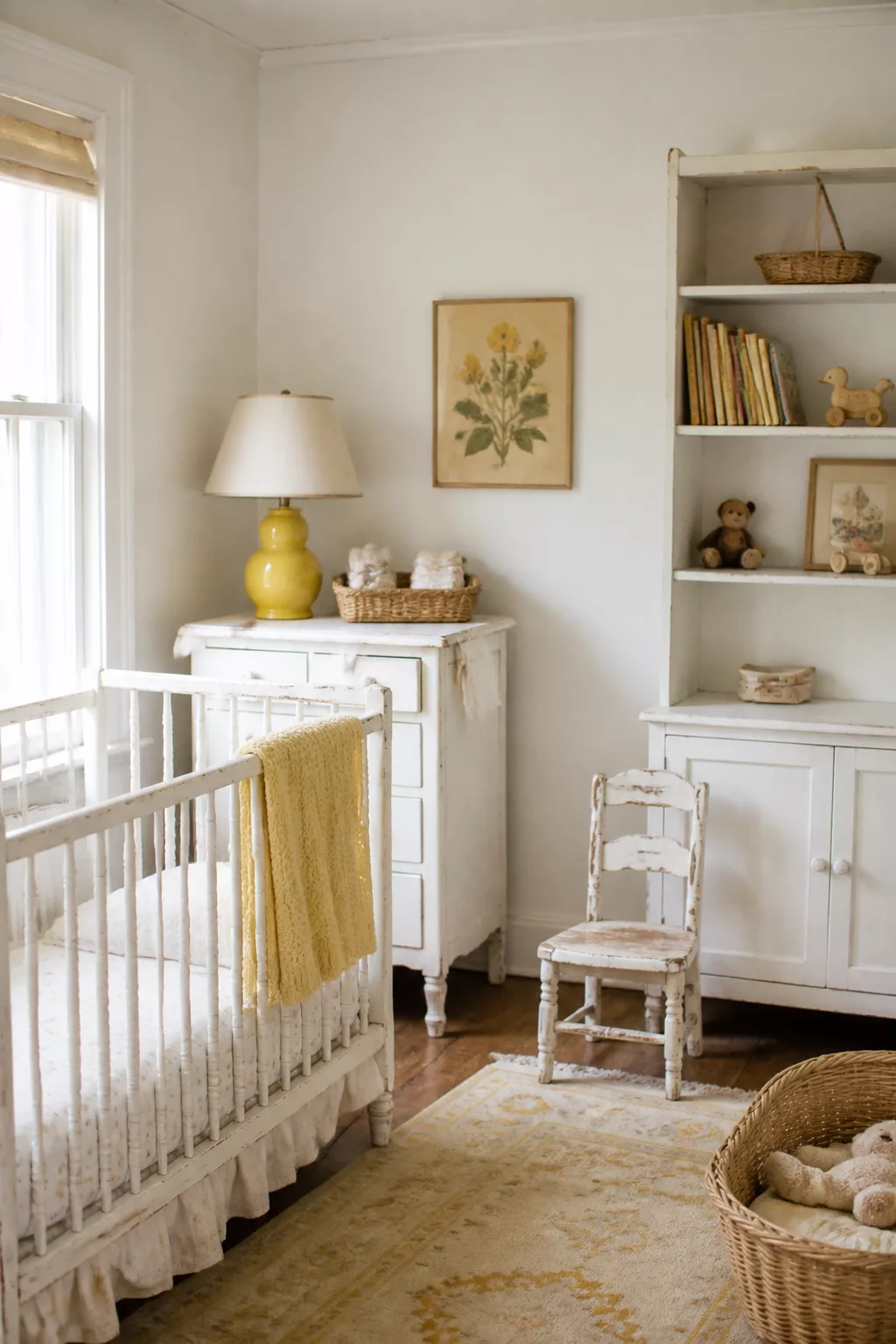 Vintage nursery design with canary yellow gourd lamp, milk-painted white crib and dresser, botanical print, and wicker accents.